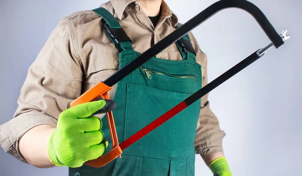 Trabalhador em roupa geral verde com serra . — Fotografia de Stock