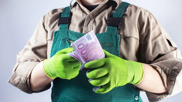 Operaio in abito verde generale con banconote in euro . — Foto Stock