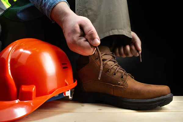 Trabalhador com capacete amarrando botas de couro . — Fotografia de Stock