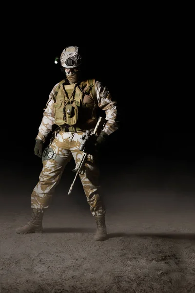 Fully equipped desert soldier standing with rifle on dark backgr