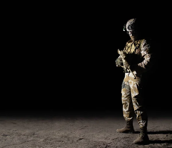 Voll ausgerüsteter Soldat mit Gewehr auf dunklem Hintergrund. — Stockfoto