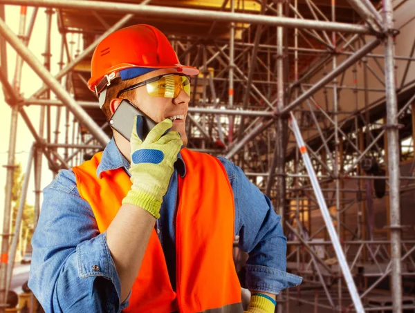 Trabalhador masculino em capacete e roupa de trabalho falando em um telefone . — Fotografia de Stock