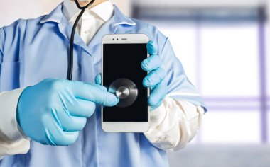 Steteskoplu üniformalı bir doktorun akıllı telefonu tutup dinlediği bir fotoğraf..