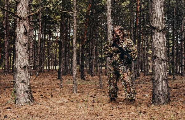 照片上是一个带着十字弓站在树林里的伪装森林狙击手猎人 — 图库照片