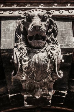 Bir taş aslan heykeli. Bina üzerinde kabartma resmi..