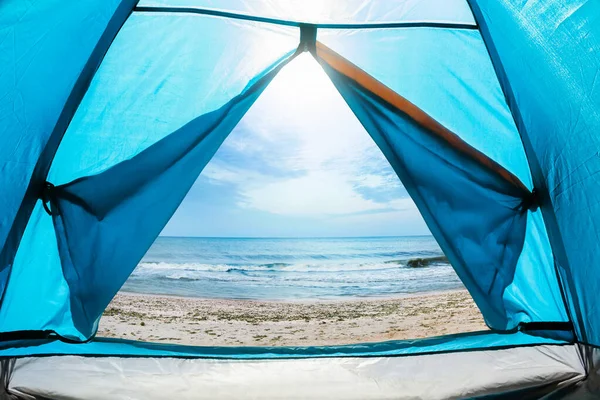 照片上是一个阳光灿烂的日子 从蓝色露营帐篷的门向海滨望去 — 图库照片