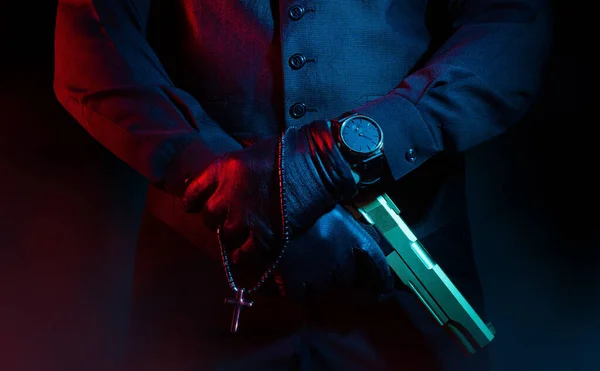 黒い背景の上に十字架と銃を保持スーツと革の手袋で男性マフィアの犯罪者の写真 — ストック写真
