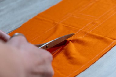 Ev yapımı dikiş dikmek. desen, makas, mezura ve dikiş. Terzi eskiz çizgilerindeki kıyafet detaylarını kesiyor.