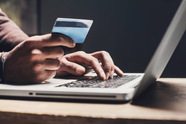 Dizüstü bilgisayar kullanan ve evde kredi kartı tutan bir adam. Ofiste çalışan genç bir iş adamı ya da girişimci. Çevrimiçi alışveriş, e-ticaret, İnternet bankacılığı, finans ve serbest konsept