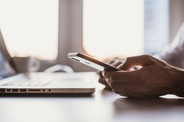 Genç adam evde dizüstü bilgisayar ve akıllı telefon kullanıyor. İş adamı ofiste telefonla mesajlaşıyordu. İş, evden çalışma, uzaktan eğitim, çevrimiçi öğrenme, öğrenim kavramı