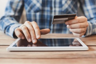 Kredi kartı tutan ve evde dizüstü bilgisayar kullanan bir adam, bilgisayar, online alışveriş, e-ticaret, internet bankacılığı, harcama para konsepti üzerinde çalışan bir iş adamı veya girişimci.