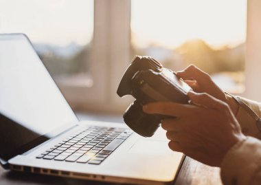 Bilgisayar ve DSLR dijital kamerasıyla çalışan bir fotoğrafçı. Fotoğraflara bakan profesyonel gazeteci ya da serbest çalışan.