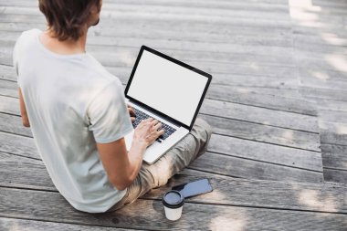 Genç yakışıklı adamlar şehirde dizüstü bilgisayar kullanıyor. Gülümseyen öğrenci kahve molası veriyor. Modern yaşam tarzı, bağlantı, iş konsepti