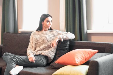 Genç bayan oturma odasındaki kanepede dinleniyor. Günlük tarz kapalı çekim.