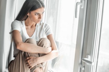 Pencerenin arkasındaki güzel genç kadın portresi. Çekici Kafkas model kız. Yumuşak güneş ışığı. Gün doğumu ya da gün batımı.