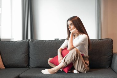 Genç bayan oturma odasındaki kanepede dinleniyor. Günlük tarz kapalı çekim.