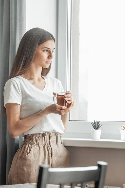 Beautiful woman drinking morning tea behind window. Challenge of a new day. Copy space