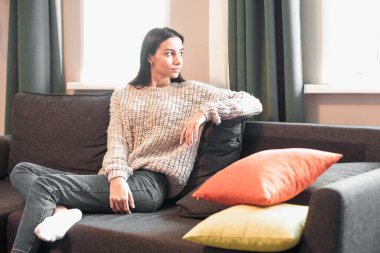 Genç bayan oturma odasındaki kanepede dinleniyor. Günlük tarz kapalı çekim.