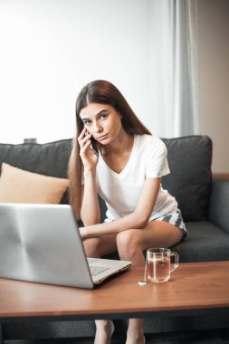 Modern dizüstü bilgisayarı olan genç bir kadın evdeki kanepede oturuyor. Boş zamanlarında internette gezinen mutlu kız... 