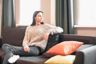 Genç bayan oturma odasındaki kanepede dinleniyor. Günlük tarz kapalı çekim.