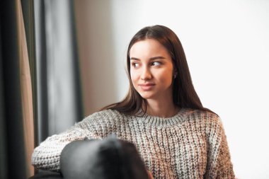 Genç bayan oturma odasındaki kanepede dinleniyor. Günlük tarz kapalı çekim.