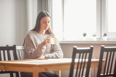 Güzel genç bayan sıcak içecek içiyor. Çekici kız evde dinleniyor.
