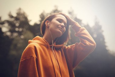 Parktaki hippi çekici kız kulaklık kullanıyor. Müzik dinleyen güzel bir kadın