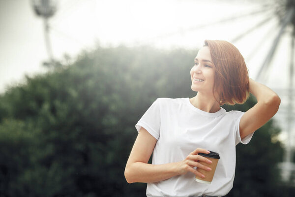 Young city girl with paper coffee cup. Attractive hipster woman with hot drink