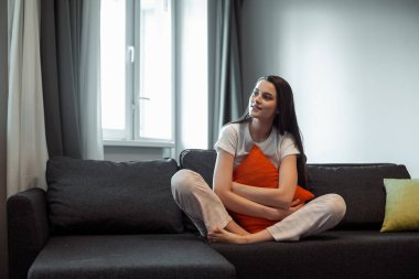 Genç bayan oturma odasındaki kanepede dinleniyor. Günlük tarz kapalı çekim.