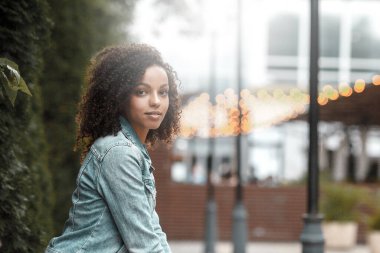 Güneşli şehir sokağındaki mutlu melez kız. Moda kadın portresi