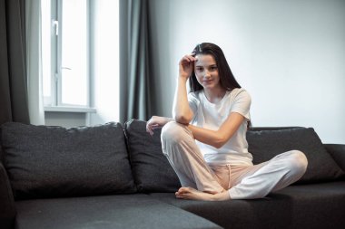 Genç bayan oturma odasındaki kanepede dinleniyor. Günlük tarz kapalı çekim.