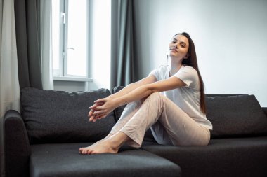 Genç bayan oturma odasındaki kanepede dinleniyor. Günlük tarz kapalı çekim.