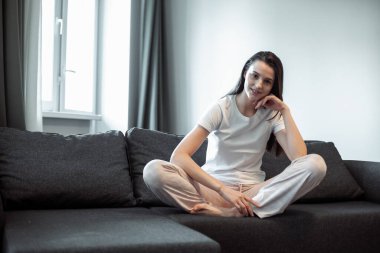 Genç bayan oturma odasındaki kanepede dinleniyor. Günlük tarz kapalı çekim.