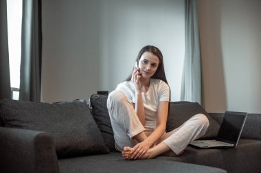 Modern dizüstü bilgisayarı olan genç bir kadın evdeki kanepede oturuyor. Boş zamanlarında internette gezinen mutlu kız... 