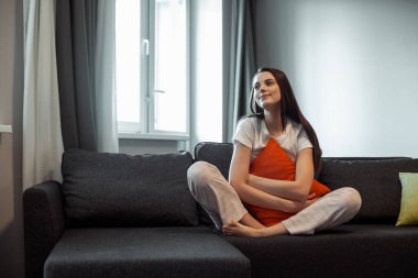 Genç bayan oturma odasındaki kanepede dinleniyor. Günlük tarz kapalı çekim.