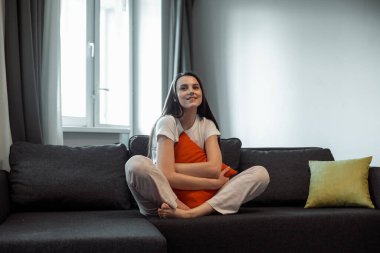 Genç bayan oturma odasındaki kanepede dinleniyor. Günlük tarz kapalı çekim.