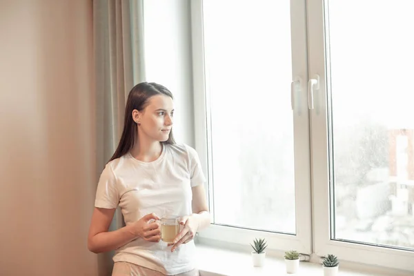 Beautiful woman drinking morning tea behind window. Challenge of a new day. Copy space