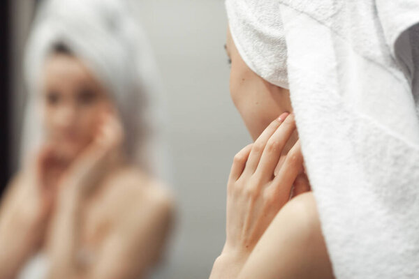 Young woman in bathroom behind mirror. Skincare  treatment concept