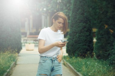 Şehir sahnesinde cep telefonlu şık bir genç kadın. Hippi modası modeli