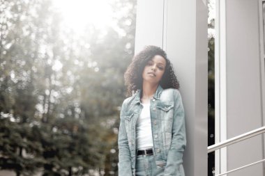 Caddedeki siyah kıvırcık kız. Güneşli yaz şehri. Genç kadın kot tarzı.