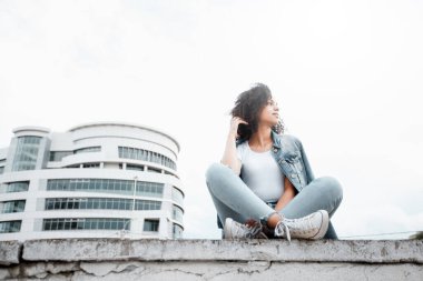 Caddedeki siyah kıvırcık kız. Güneşli yaz şehri. Genç kadın kot tarzı.