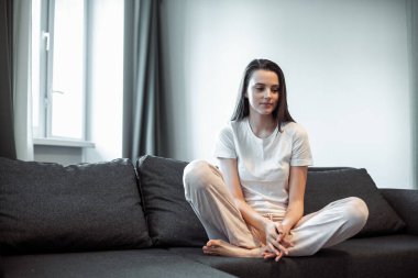 Genç bayan oturma odasındaki kanepede dinleniyor. Günlük tarz kapalı çekim.