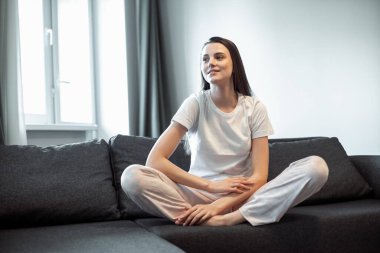 Genç bayan oturma odasındaki kanepede dinleniyor. Günlük tarz kapalı çekim.