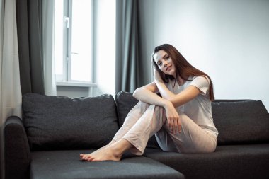 Genç bayan oturma odasındaki kanepede dinleniyor. Günlük tarz kapalı çekim.