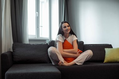 Genç bayan oturma odasındaki kanepede dinleniyor. Günlük tarz kapalı çekim.