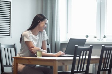 Işık odasında bilgisayarla çalışan bir kız. Modern iç mekanlarda sosyal ağda kadın sohbeti