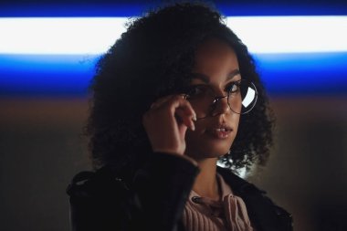 Genç, kıvırcık, Afro-Amerikan kızın portresi. Gece şehir ışıkları. Neon aydınlatması