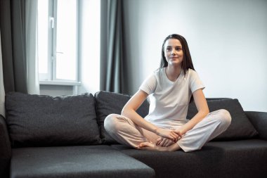 Genç bayan oturma odasındaki kanepede dinleniyor. Günlük tarz kapalı çekim.