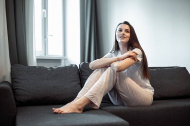 Genç bayan oturma odasındaki kanepede dinleniyor. Günlük tarz kapalı çekim.