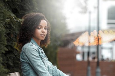 Caddedeki siyah kıvırcık kız. Güneşli yaz şehri. Genç kadın kot tarzı.